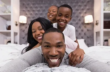 Smiling family of four lying together on a bed.