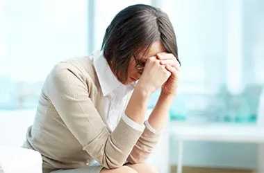 Person sitting with head in hands, appearing thoughtful or stressed.